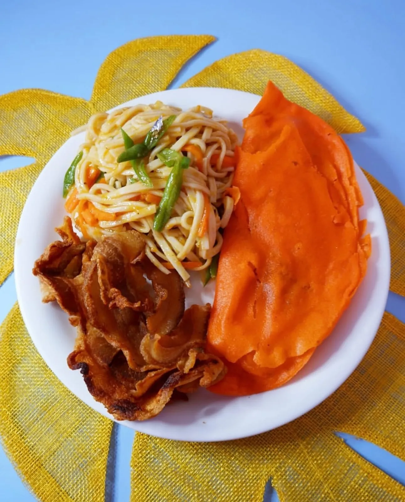 Ilocos empanada, pancit and crisp bacon bagnet arranged on a white plate